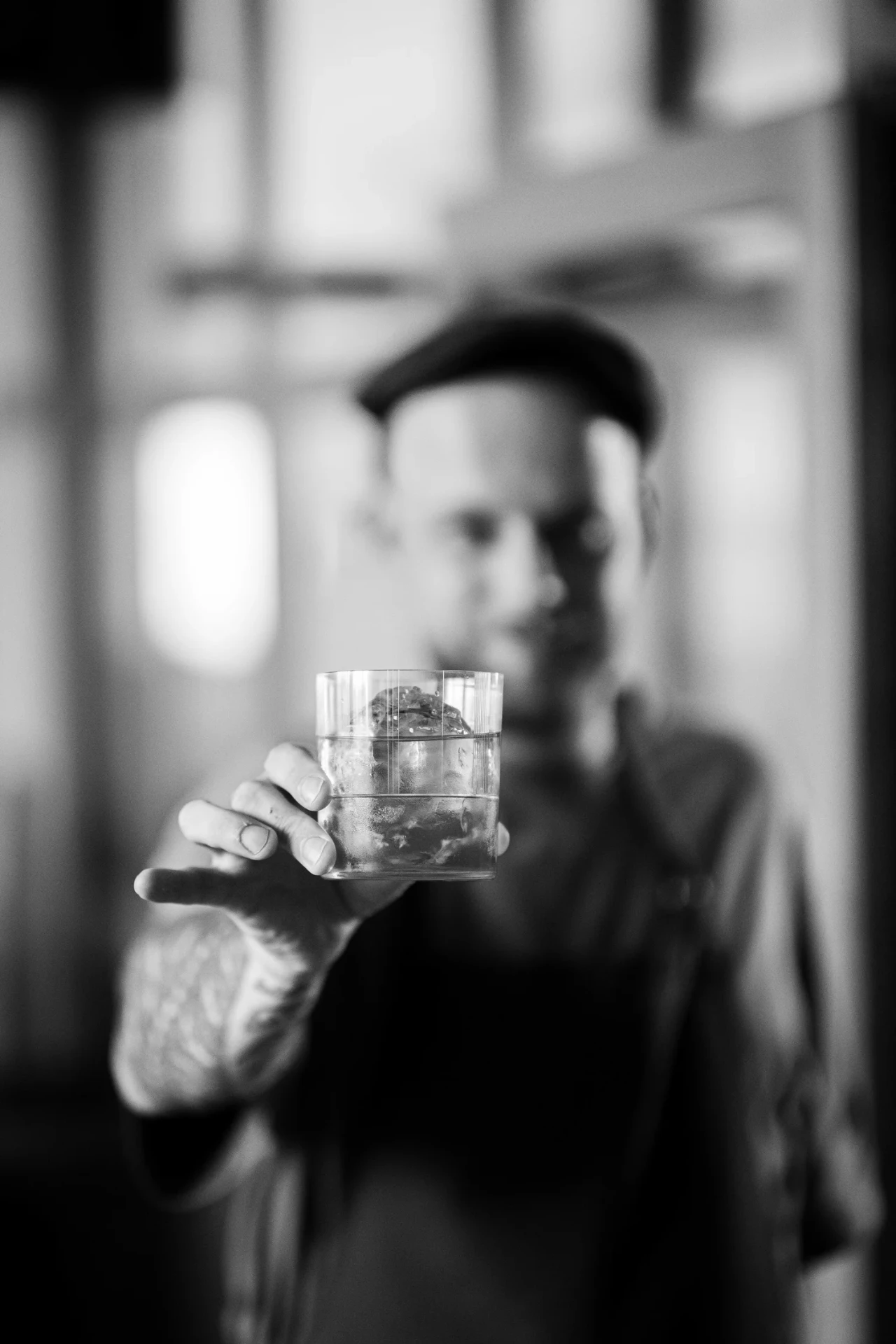 Barman houdt een tumbler met cocktail voor de lens